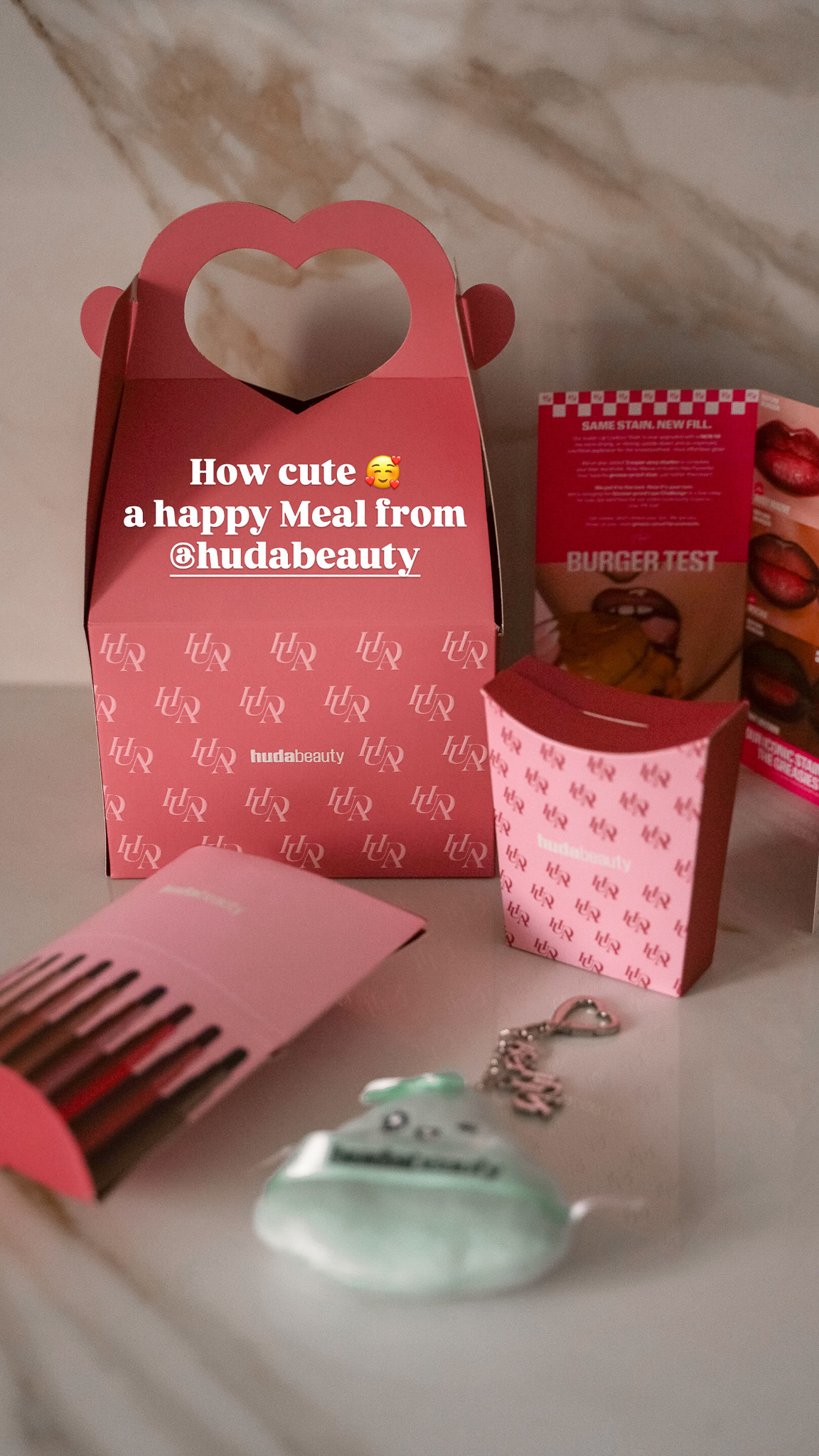 Huda Beauty Happy-Meal-Box mit Lip-Produkten, Schlüsselanhänger und Burger-Test-Flyer