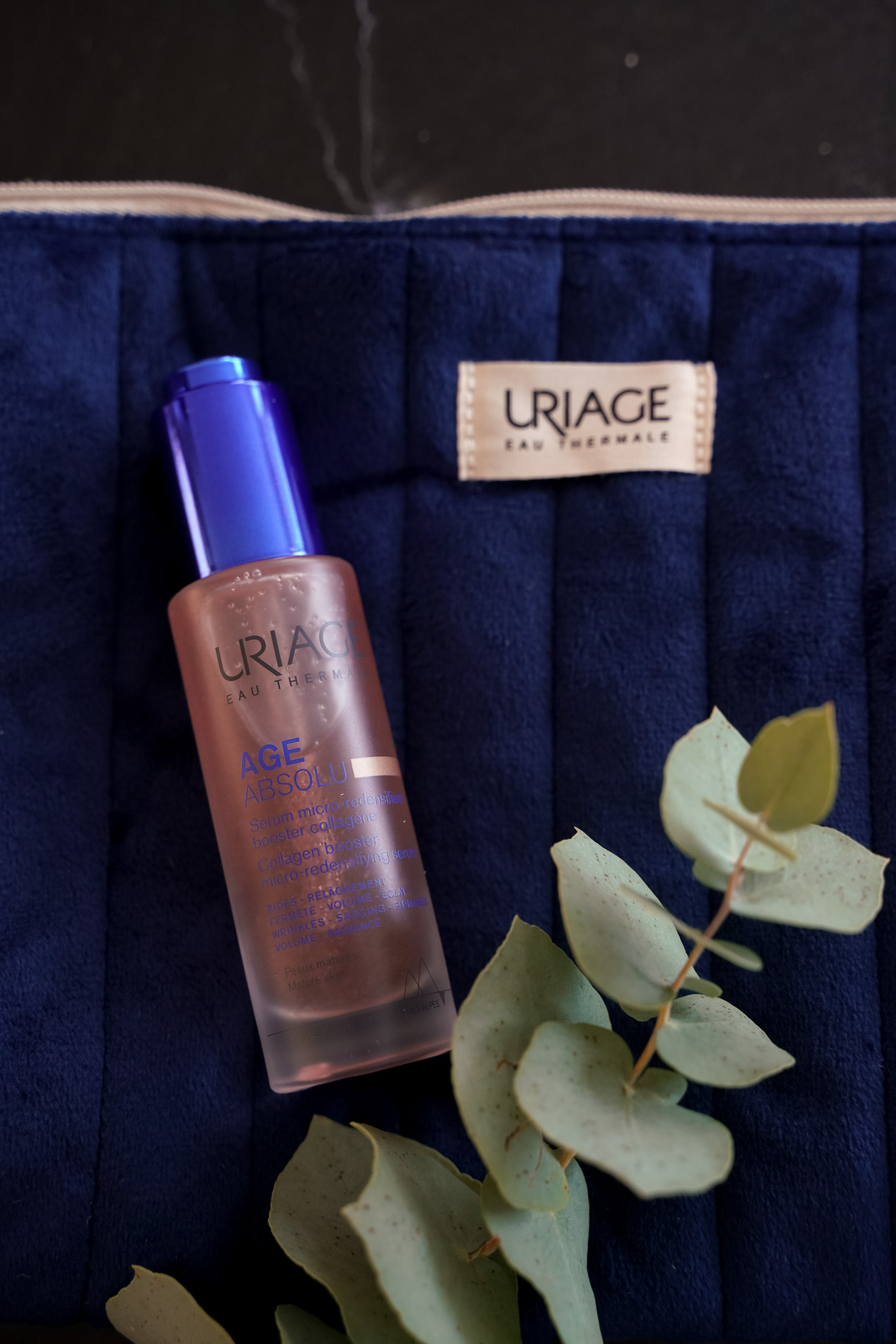 Uriage Age Absolu Collagen Booster Serum auf blauer Kosmetiktasche